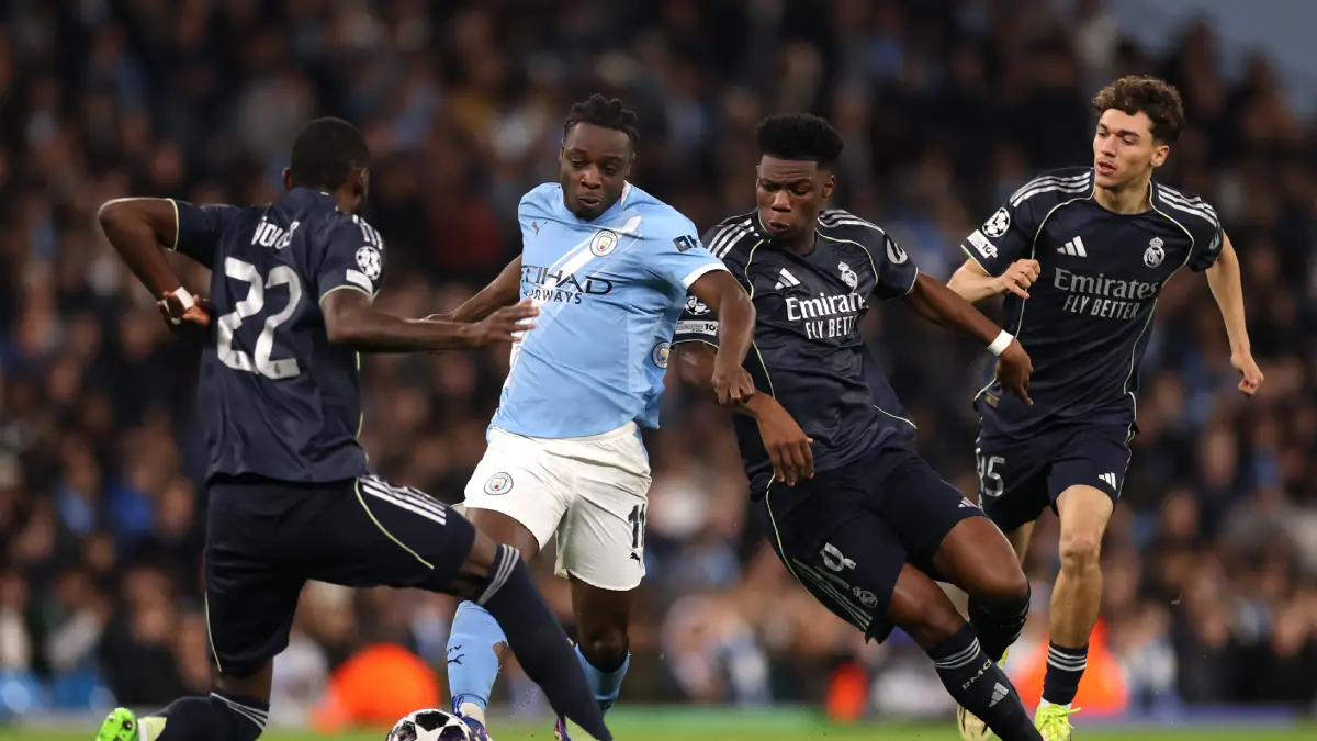 MANCHESTER, ENGLAND - MARCH 17: Jeremy Doku of Manchester City runs with the ball whilst under pressure from Antonio Ruediger and Aurelien Tchouameni during the UEFA Champions League 2025/26 Round of 16 Second Leg match between Manchester City FC and Real Madrid CF at City of Manchester Stadium on March 17, 2026 in Manchester, England. (Photo by Carl Recine/Getty Images)