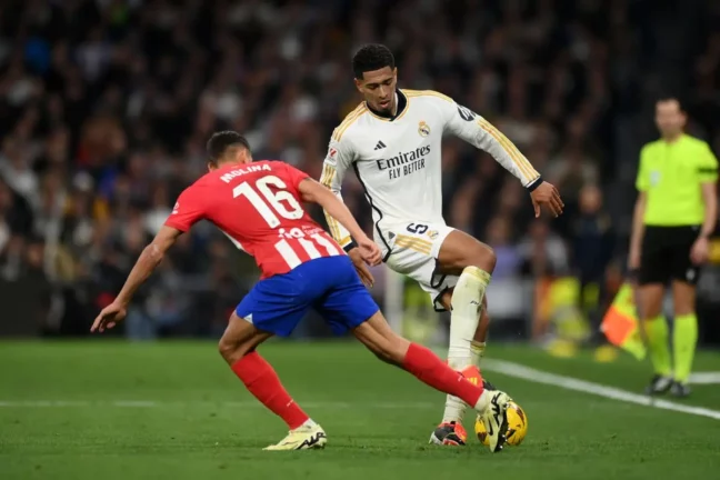 MADRID, SPAIN - FEBRUARY 04: Jude Bellingham of Real Madrid on the ball whilst under pressure from Nahuel Molina of Atletico Madrid during the LaLiga EA Sports match between Real Madrid CF and Atletico Madrid at Estadio Santiago Bernabeu on February 04, 2024 in Madrid, Spain. (Photo by Denis Doyle/Getty Images).