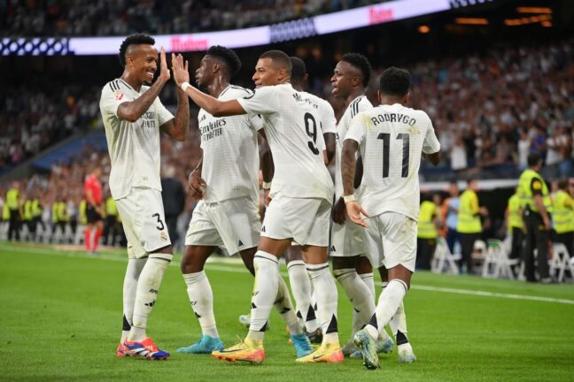 MADRID, SPAIN - SEPTEMBER 01: Kylian Mbappe of Real Madrid (C) celebrates scoring his team's first goal with teammates Eder Militao, Vinicius Junior and Rodrygo during the LaLiga match between Real Madrid CF and Real Betis Balompie at Estadio Santiago Bernabeu on September 01, 2024 in Madrid, Spain. (Photo by Denis Doyle/Getty Images).
