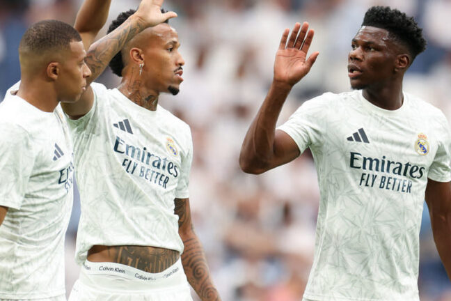 MADRID, SPAIN - AUGUST 25: Kylian Mbappe of Real Madrid CF interacts with teammates Eder Militao and Aurelien Tchouameni during the La Liga match between Real Madrid CF and Real Valladolid CF at Estadio Santiago Bernabeu on August 25, 2024 in Madrid, Spain. (Photo by Florencia Tan Jun/Getty Images).