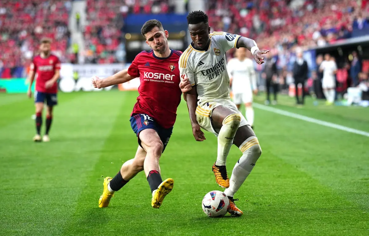 PAMPLONA, SPAIN - MARCH 16: Vinicius Junior of Real Madrid is challenged by Jesus Areso of CA Osasuna during the LaLiga EA Sports match between CA Osasuna and Real Madrid CF at Estadio El Sadar on March 16, 2024 in Pamplona, Spain. (Photo by Juan Manuel Serrano Arce/Getty Images).