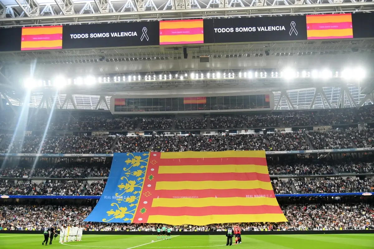 MADRID, SPAIN - NOVEMBER 09: Players from both teams observe a minutes silences in memory of the victims for the recent floods in Valencia, as fans display the flag from the City of Valencia prior to the LaLiga match between Real Madrid CF and CA Osasuna at Estadio Santiago Bernabeu on November 09, 2024 in Madrid, Spain. (Photo by Denis Doyle/Getty Images)