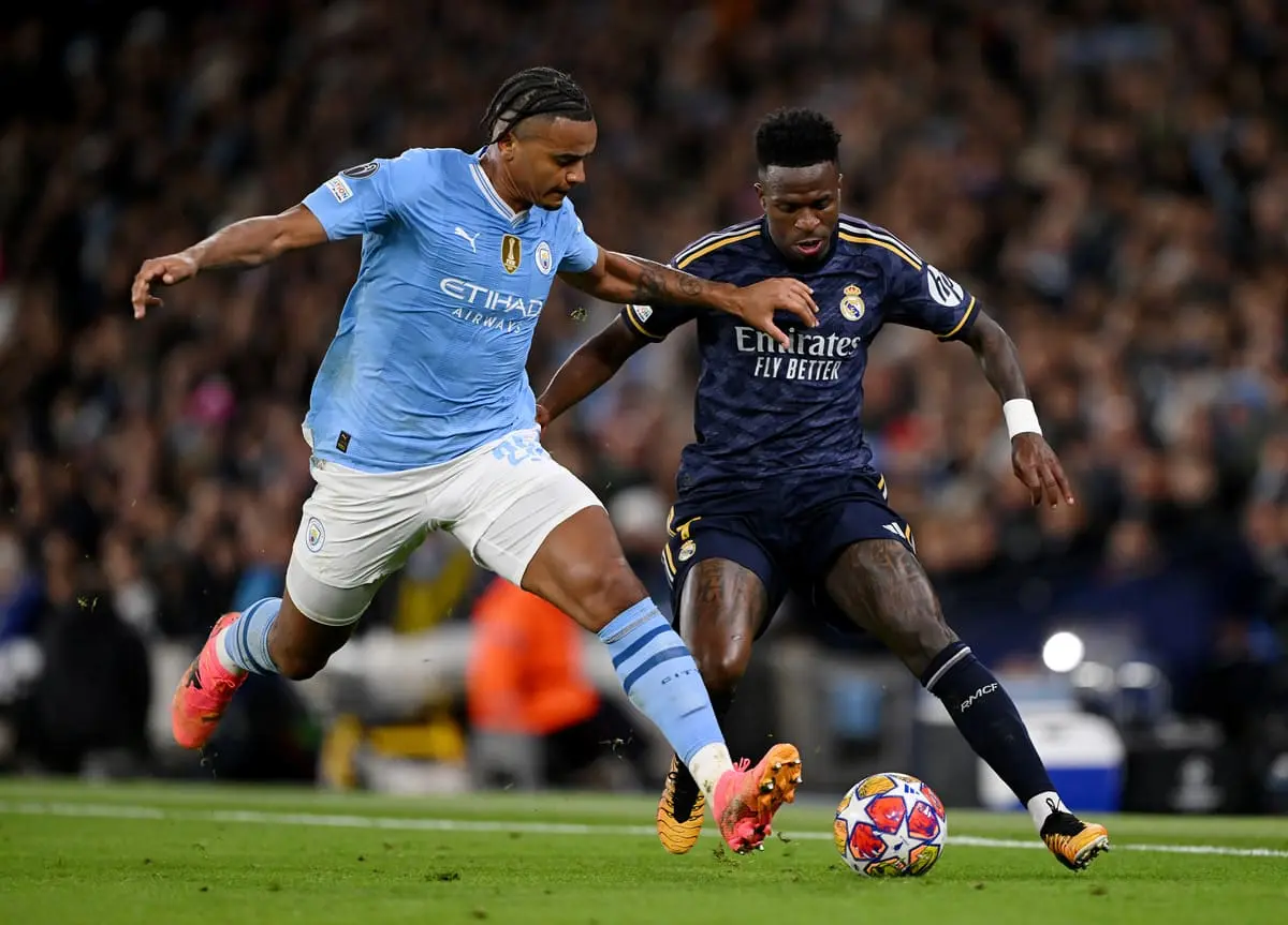 MANCHESTER, ENGLAND - APRIL 17: Vinicius Junior of Real Madrid is challenged by Manuel Akanji of Manchester City during the UEFA Champions League quarter-final second leg match between Manchester City and Real Madrid CF at Etihad Stadium on April 17, 2024 in Manchester, England. (Photo by Stu Forster/Getty Images).