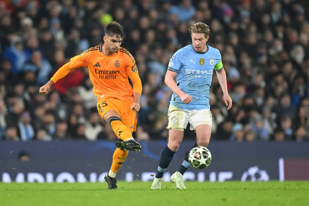 MANCHESTER, ENGLAND - FEBRUARY 11: Raul Asencio of Real Madrid makes a pass whilst under pressure from Kevin De Bruyne of Manchester City during the UEFA Champions League 2024/25 League Knockout Play-off first leg match between Manchester City and Real Madrid C.F. at Manchester City Stadium on February 11, 2025 in Manchester, England. (Photo by Michael Regan/Getty Images).