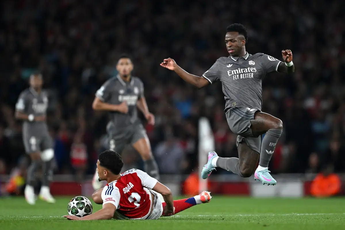 LONDON, ENGLAND - APRIL 08: William Saliba of Arsenal makes a tackle on Vinicius Junior of Real Madrid during the UEFA Champions League 2024/25 Quarter Final First Leg match between Arsenal FC and Real Madrid C.F. at Emirates Stadium on April 08, 2025 in London, England. (Photo by Shaun Botterill/Getty Images)