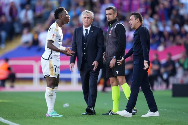BARCELONA, SPAIN - OCTOBER 28: Vinicius Junior of Real Madrid and Xavi, Head Coach of FC Barcelona, interact during the LaLiga EA Sports match between FC Barcelona and Real Madrid CF at Estadi Olimpic Lluis Companys on October 28, 2023 in Barcelona, Spain. (Photo by Alex