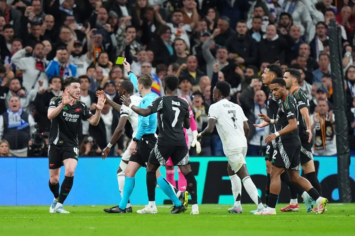 MADRID, SPAIN - APRIL 16: Declan Rice of Arsenal reacts after he is shown a yellow card by Referee Francois Letexier for a foul on Kylian Mbappe of Real Madrid (not pictured), resulting in a penalty kick awarded which is later overturned following a VAR check during the UEFA Champions League 2024/25 Quarter Final Second Leg match between Real Madrid C.F. and Arsenal FC at Estadio Santiago Bernabeu on April 16, 2025 in Madrid, Spain. (Photo by Angel Martinez/Getty Images)