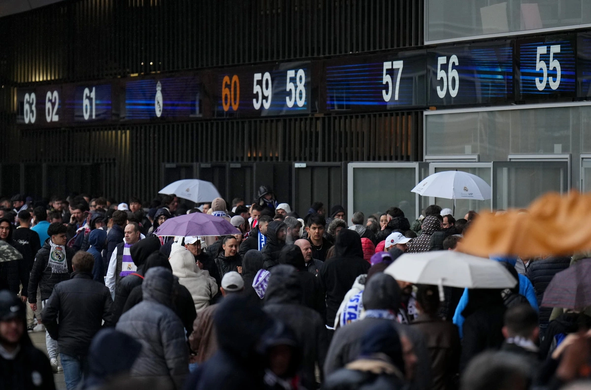 MADRID, SPAIN - APRIL 16: Real Madrid fans, arriving at the stadium, shelter from the rain with umbrellas prior to the UEFA Champions League 2024/25 Quarter Final Second Leg match between Real Madrid C.F. and Arsenal FC at Estadio Santiago Bernabeu on April 16, 2025 in Madrid, Spain. (Photo by Angel Martinez/Getty Images)
