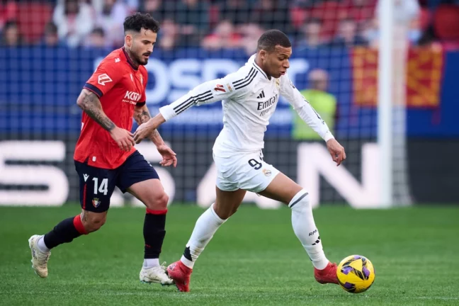 PAMPLONA, SPAIN - FEBRUARY 15: Kylian Mbappe of Real Madrid duels for the ball with Ruben Garcia of CA Osasuna during the LaLiga match between CA Osasuna and Real Madrid CF at Estadio El Sadar on February 15, 2025 in Pamplona, Spain. (Photo by Juan Manuel Serrano Arce/Getty Images)