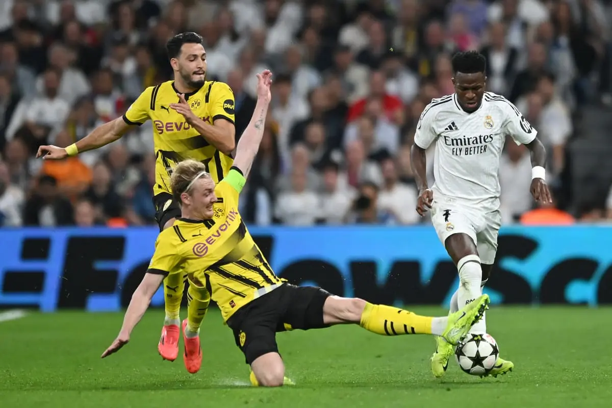 MADRID, SPAIN - OCTOBER 22: Vinicius Junior of Real Madrid is challenged by Julian Brandt of Borussia Dortmund during the UEFA Champions League 2024/25 League Phase MD3 match between Real Madrid C.F. and Borussia Dortmund at Estadio Santiago Bernabeu on October 22, 2024 in Madrid, Spain. (Photo by Denis Doyle/Getty Images)