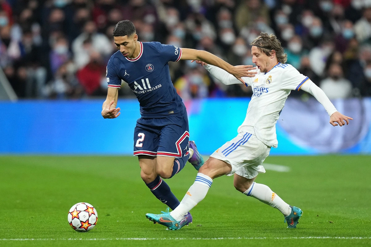 MADRID, SPAIN - MARCH 09: Achraf Hakimi of Paris Saint-Germain is challenged by Luka Modric of Real Madrid during the UEFA Champions League Round Of Sixteen Leg Two match between Real Madrid and Paris Saint-Germain at Estadio Santiago Bernabeu on March 09, 2022 in