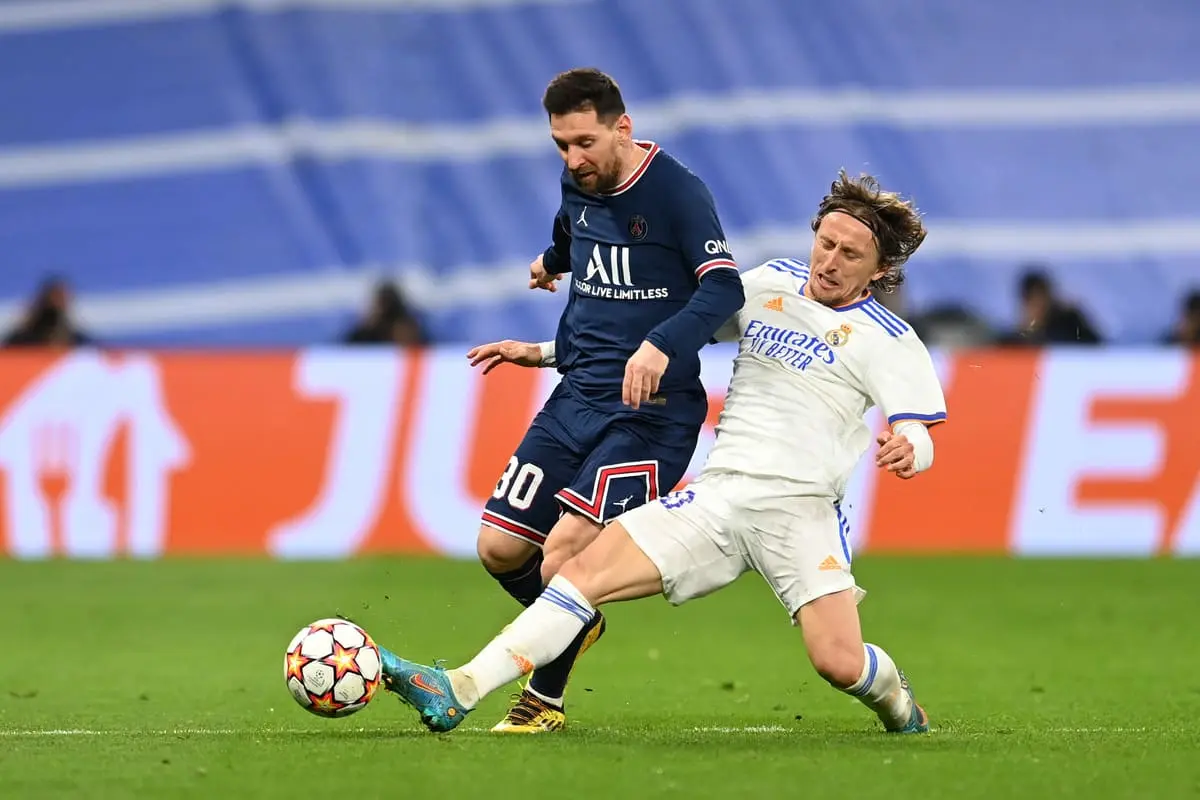 MADRID, SPAIN - MARCH 09: Lionel Messi of Paris Saint-Germain is tackled by Luka Modric of Real Madrid during the UEFA Champions League Round Of Sixteen Leg Two match between Real Madrid and Paris Saint-Germain at Estadio Santiago Bernabeu on March 09, 2022 in Madrid, Spain. (Photo by David Ramos/Getty Images)