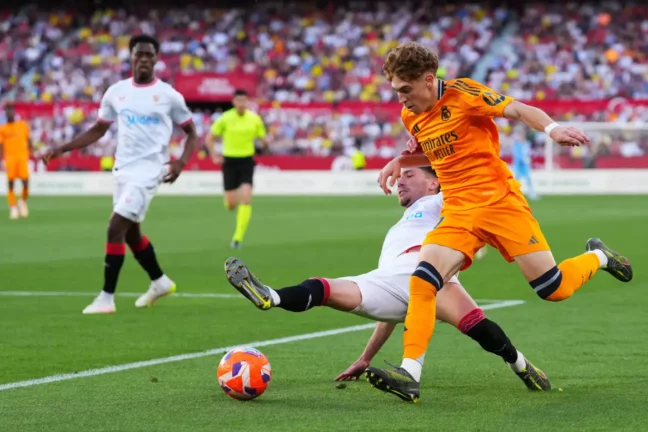 SEVILLE, SPAIN - MAY 18: Victor Munoz of Real Madrid is challenged by Jose Angel Carmona of Sevilla FC during the LaLiga match between Sevilla FC and Real Madrid CF at Estadio Ramon Sanchez Pizjuan on May 18, 2025 in Seville, Spain. (Photo by Angel Martinez/Getty Images)