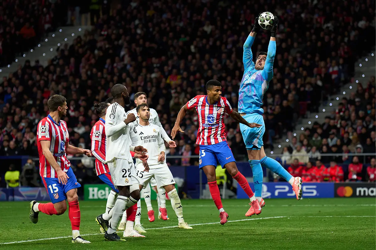 MADRID, SPAIN - MARCH 12: Thibaut Courtois of Real Madrid catches the ball whilst under pressure from Reinildo Mandava of Atletico de Madrid during the derbi in UEFA Champions League 2024/25 UEFA Champions League 2024/25 Round of 16 second leg match between Atletico de Madrid and Real Madrid C.F. at Riyadh Air Metropolitano on March 12, 2025 in Madrid, Spain. (Photo by Angel Martinez/Getty Images)