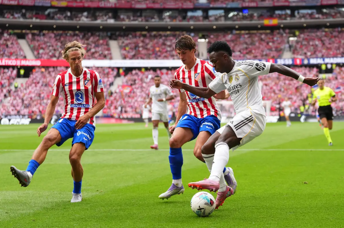MADRID, SPAIN - SEPTEMBER 27: Vinicius Junior of Real Madrid is put under pressure by Marcos Llorente (L) and Robin Le Normand of Atletico de Madrid during the LaLiga EA Sports match between Atletico de Madrid and Real Madrid CF at Riyadh Air Metropolitano on September 27, 2025 in Madrid, Spain. (Photo by Angel Martinez/Getty Images)