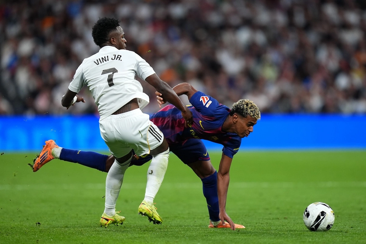 MADRID, SPAIN - OCTOBER 26: Lamine Yamal of FC Barcelona is challenged by Vinicius Jr of Real Madrid during the LaLiga EA Sports match between Real Madrid CF and FC Barcelona at Estadio Santiago Bernabeu on October 26, 2025 in Madrid, Spain. (Photo by Angel Martinez/Getty Images)