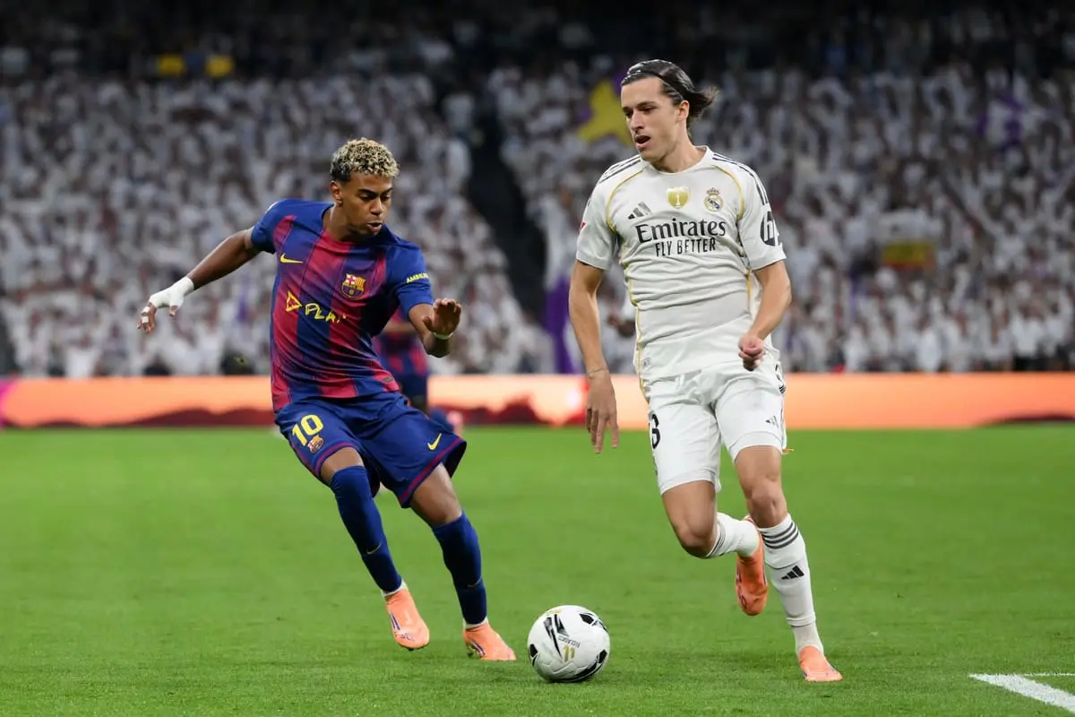 MADRID, SPAIN - OCTOBER 26: Alvaro Carreras of Real Madrid runs with the ball whilst under pressure from Lamine Yamal of FC Barcelona during the LaLiga EA Sports match between Real Madrid CF and FC Barcelona at Estadio Santiago Bernabeu on October 26, 2025 in Madrid, Spain. (Photo by David Ramos/Getty Images).