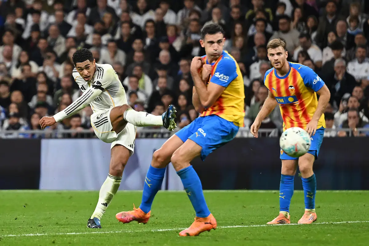 MADRID, SPAIN - NOVEMBER 01: Jude Bellingham of Real Madrid shoots past Cesar Tarrega of Valencia CF to score his team's third goal during the LaLiga EA Sports match between Real Madrid CF and Valencia CF at Estadio Santiago Bernabeu on November 01, 2025 in Madrid, Spain. (Photo by Denis Doyle/Getty Images)