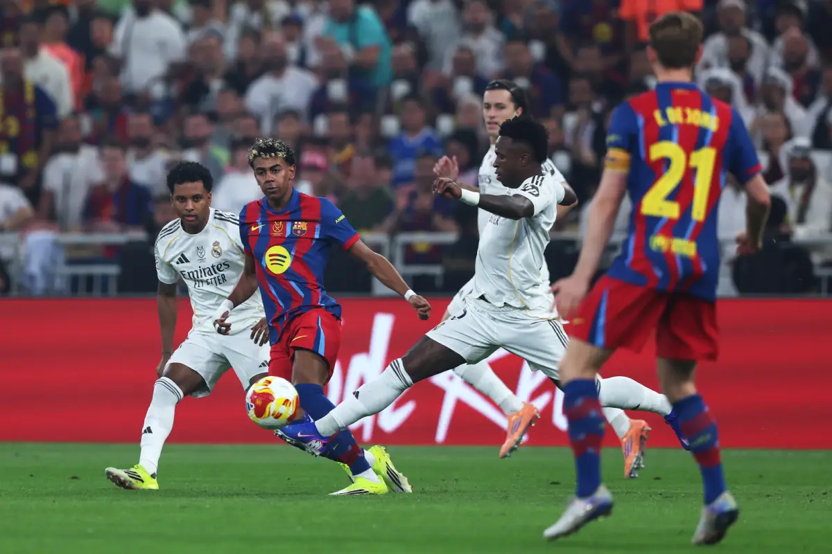 JEDDAH, SAUDI ARABIA - JANUARY 11: Vinicius Junior of Real Madrid runs with the ball whilst under pressure from Lamine Yamal of FC Barcelona during the Spanish Super Cup Final between FC Barcelona and Real Madrid at King Abdullah Sports City Hall Stadium on January 11, 2026 in Jeddah, Saudi Arabia. (Photo by Yasser Bakhsh/Getty Images)