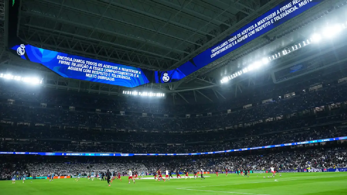 MADRID, SPAIN - FEBRUARY 25: A Real Madrid fan inside the stadium with a banner reading "Vini we are with you" prior to the UEFA Champions League 2025/26 League Knockout Play-off Second Leg match between Real Madrid C.F. and SL Benfica at Estadio Santiago Bernabeu on February 25, 2026 in Madrid, Spain. (Photo by Clive Brunskill/Getty Images)