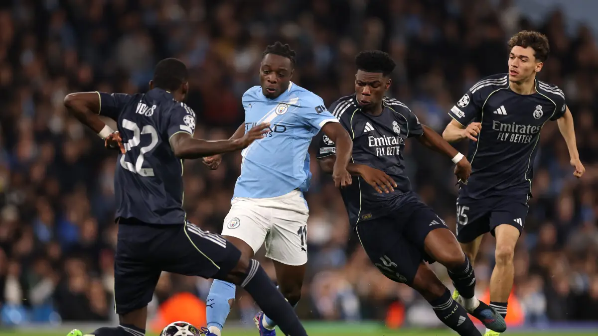 MANCHESTER, ENGLAND - MARCH 17: Jeremy Doku of Manchester City runs with the ball whilst under pressure from Antonio Ruediger and Aurelien Tchouameni during the UEFA Champions League 2025/26 Round of 16 Second Leg match between Manchester City FC and Real Madrid CF at City of Manchester Stadium on March 17, 2026 in Manchester, England. (Photo by Carl Recine/Getty Images)