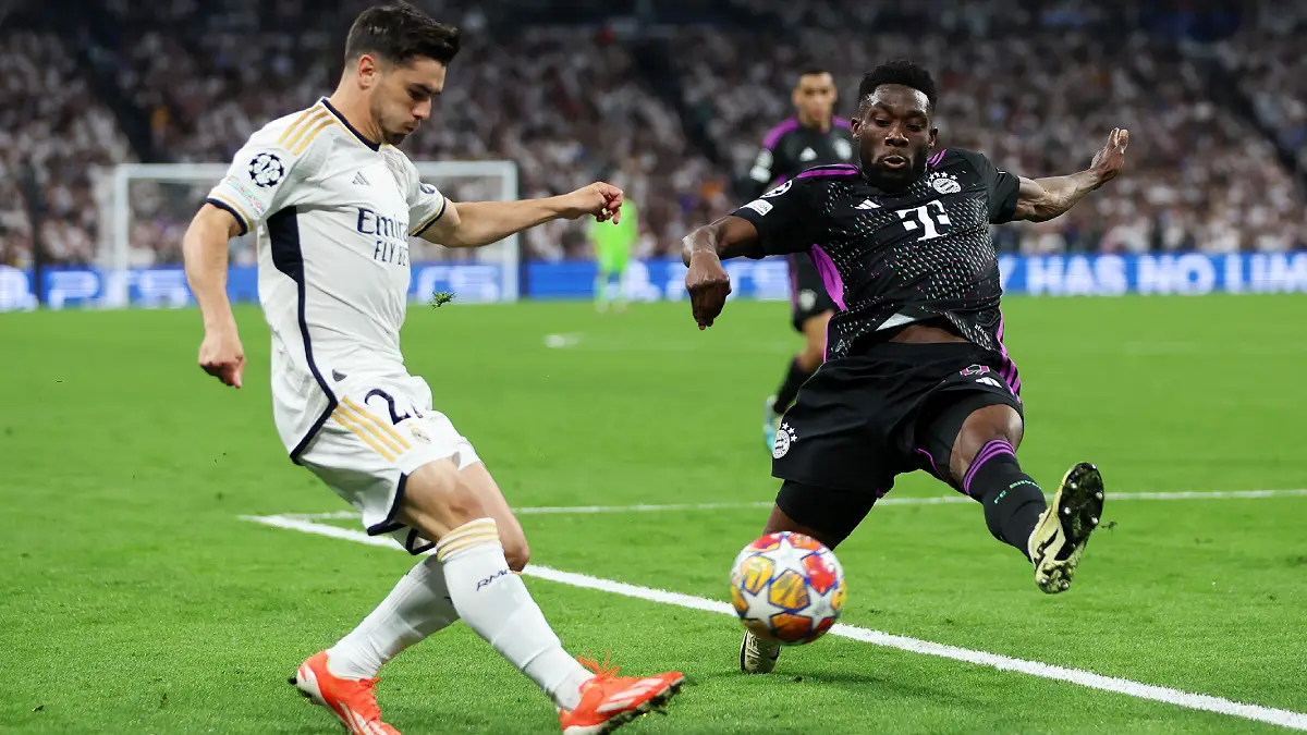 MADRID, SPAIN - MAY 08: Daniel Carvajal of Real Madrid crosses the ball whilst under pressure from Alphonso Davies of Bayern Munich during the UEFA Champions League semi-final second leg match between Real Madrid and FC Bayern München at Estadio Santiago Bernabeu on May 08, 2024 in Madrid, Spain. (Photo by Clive Brunskill/Getty Images)