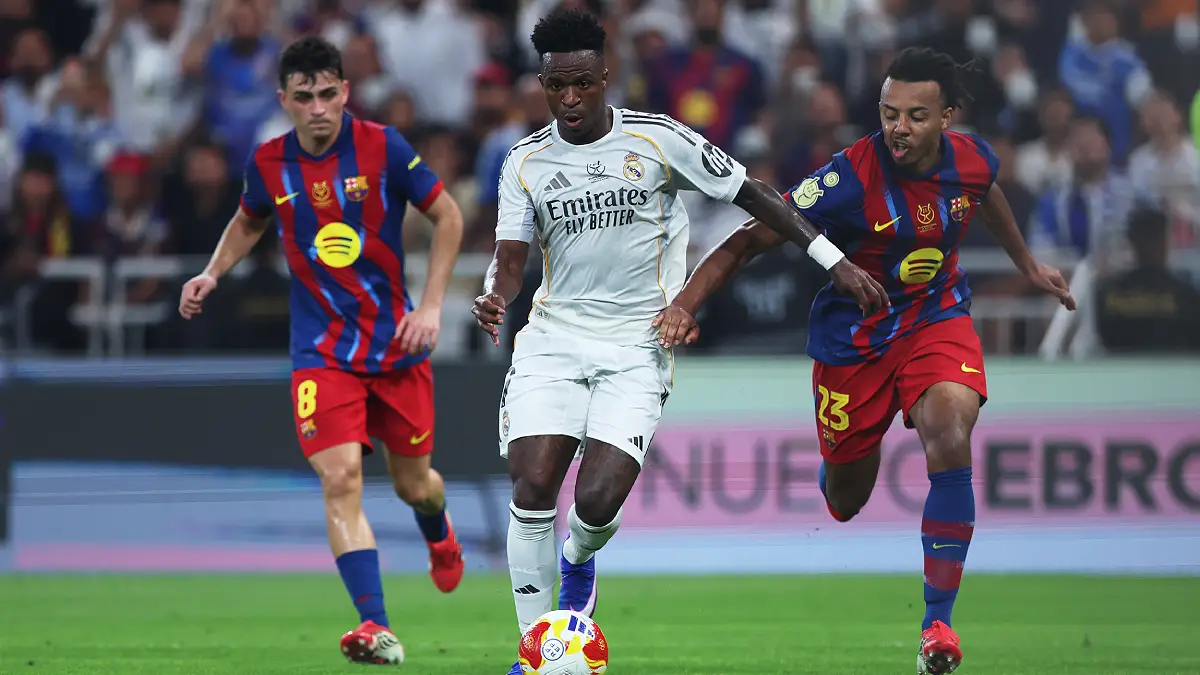 JEDDAH, SAUDI ARABIA - JANUARY 11: Vinicius Junior of Real Madrid is challenged by Jules Kounde of FC Barcelona during the Spanish Super Cup Final between FC Barcelona and Real Madrid at King Abdullah Sports City Hall Stadium on January 11, 2026 in Jeddah, Saudi Arabia. (Photo by Yasser Bakhsh/Getty Images)