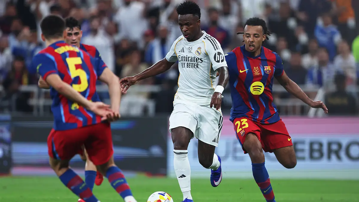 JEDDAH, SAUDI ARABIA - JANUARY 11: Vinicius Junior of Real Madrid is challenged by Jules Kounde of FC Barcelona during the Spanish Super Cup Final between FC Barcelona and Real Madrid at King Abdullah Sports City Hall Stadium on January 11, 2026 in Jeddah, Saudi Arabia. (Photo by Yasser Bakhsh/Getty Images)