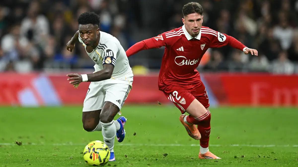 MADRID, SPAIN - DECEMBER 20: Vinicius Junior of Real Madridis challenged by Jose Angel Carmona of Sevilla FC during the LaLiga EA Sports match between Real Madrid CF and Sevilla FC at Estadio Santiago Bernabeu on December 20, 2025 in Madrid, Spain. (Photo by Denis Doyle/Getty Images)