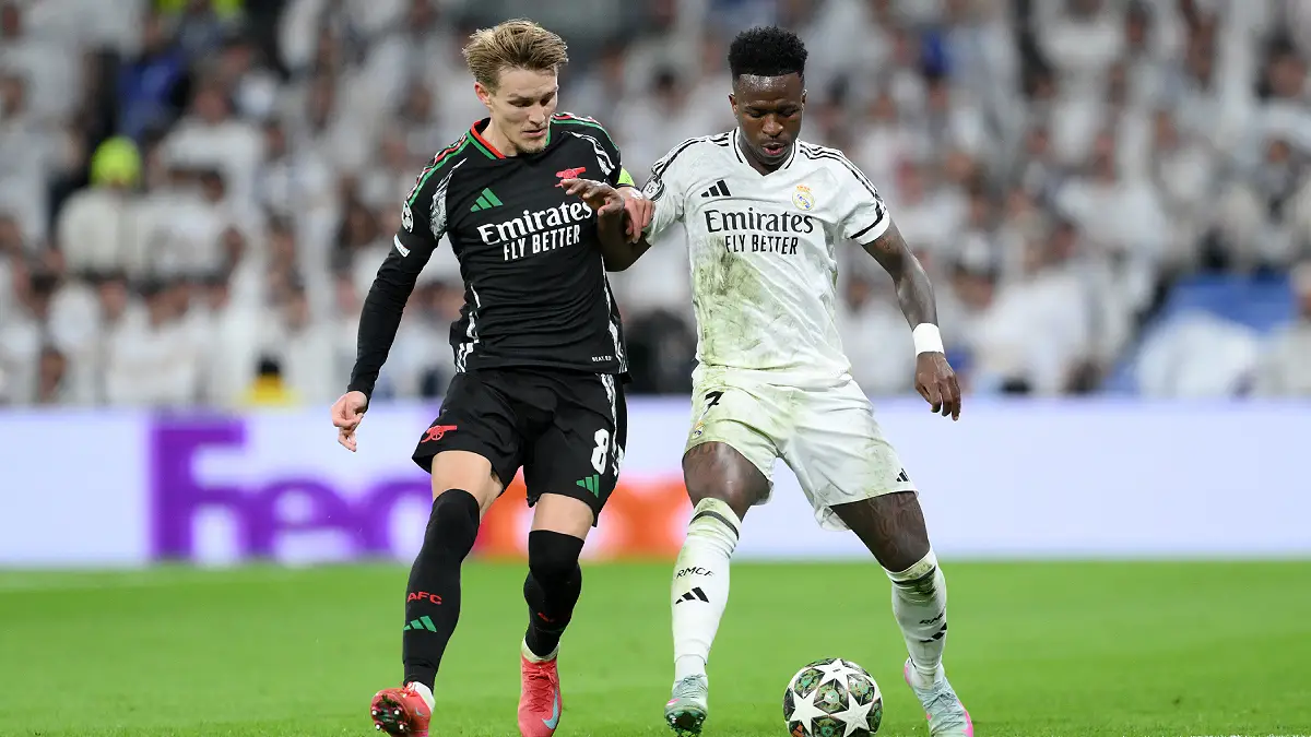 MADRID, SPAIN - APRIL 16: Martin Odegaard of Arsenal and Vinicius Junior of Real Madrid battle for possession during the UEFA Champions League 2024/25 Quarter Final Second Leg match between Real Madrid C.F. and Arsenal FC at Estadio Santiago Bernabeu on April 16, 2025 in Madrid, Spain. (Photo by David Ramos/Getty Images)